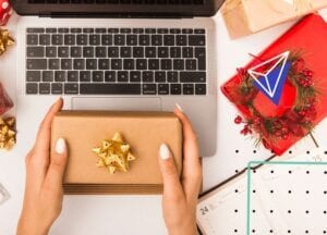 Amazon holiday selling | Person holding a gift box over a laptop